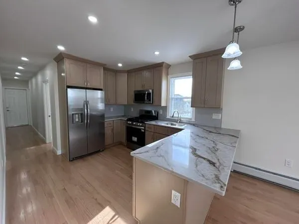 a large kitchen with granite countertop a large counter top appliances and cabinets