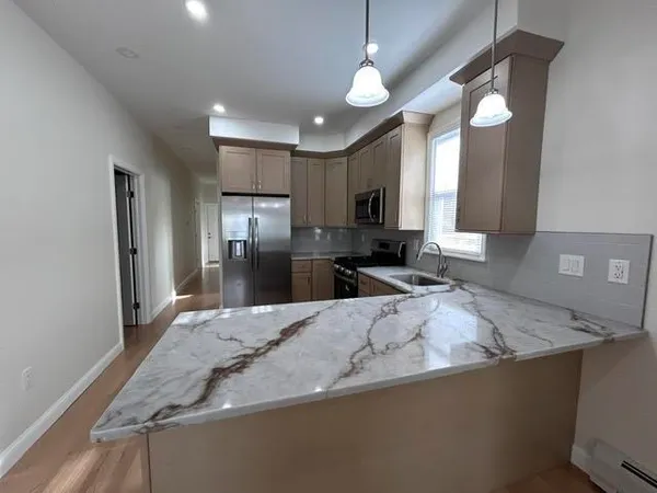 a kitchen with granite countertop a sink a counter top space stainless steel appliances and cabinets
