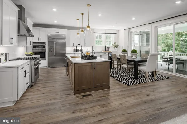 a open kitchen with stainless steel appliances granite countertop a stove top oven a sink dishwasher a dining table and chairs with wooden floor