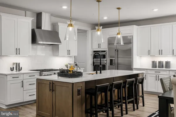a kitchen with stainless steel appliances kitchen island a table chairs sink and cabinets