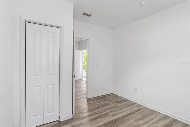 a view of an empty room with wooden floor and closet