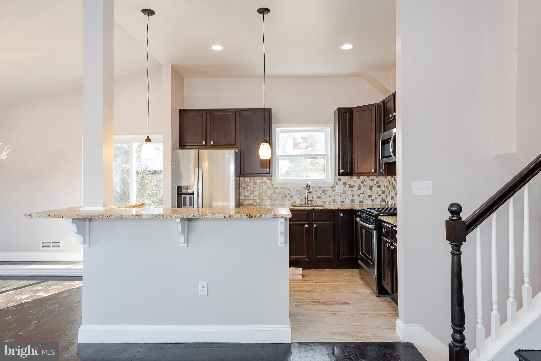 3327 Essex Road Baltimore, MD 21207 - Photo 11 of 35 a large kitchen with granite countertop a sink a counter space appliances and cabinets