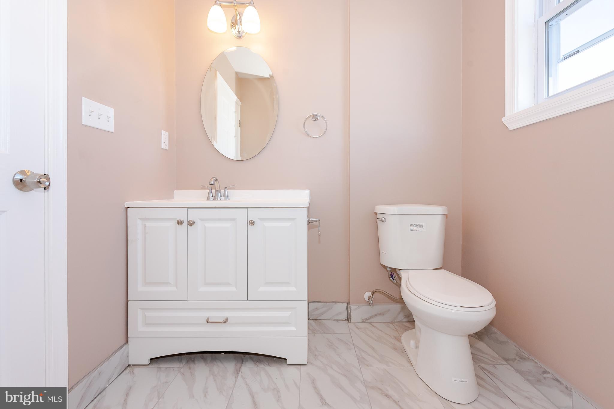 3327 Essex Road Baltimore, MD 21207 - Photo 17 of 35 a bathroom with a toilet a sink and a mirror
