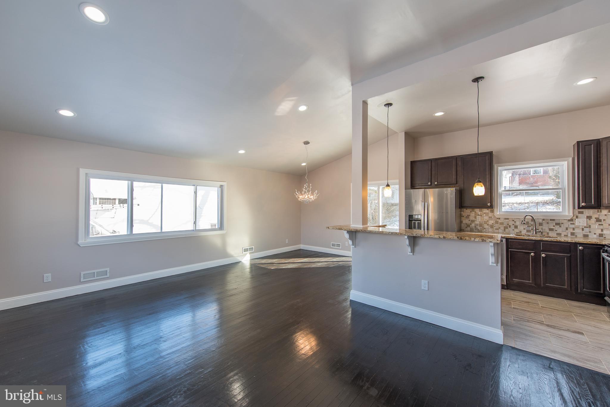 3327 Essex Road Baltimore, MD 21207 - Photo 5 of 35 a large kitchen with kitchen island a stove a sink a refrigerator and a wooden floor