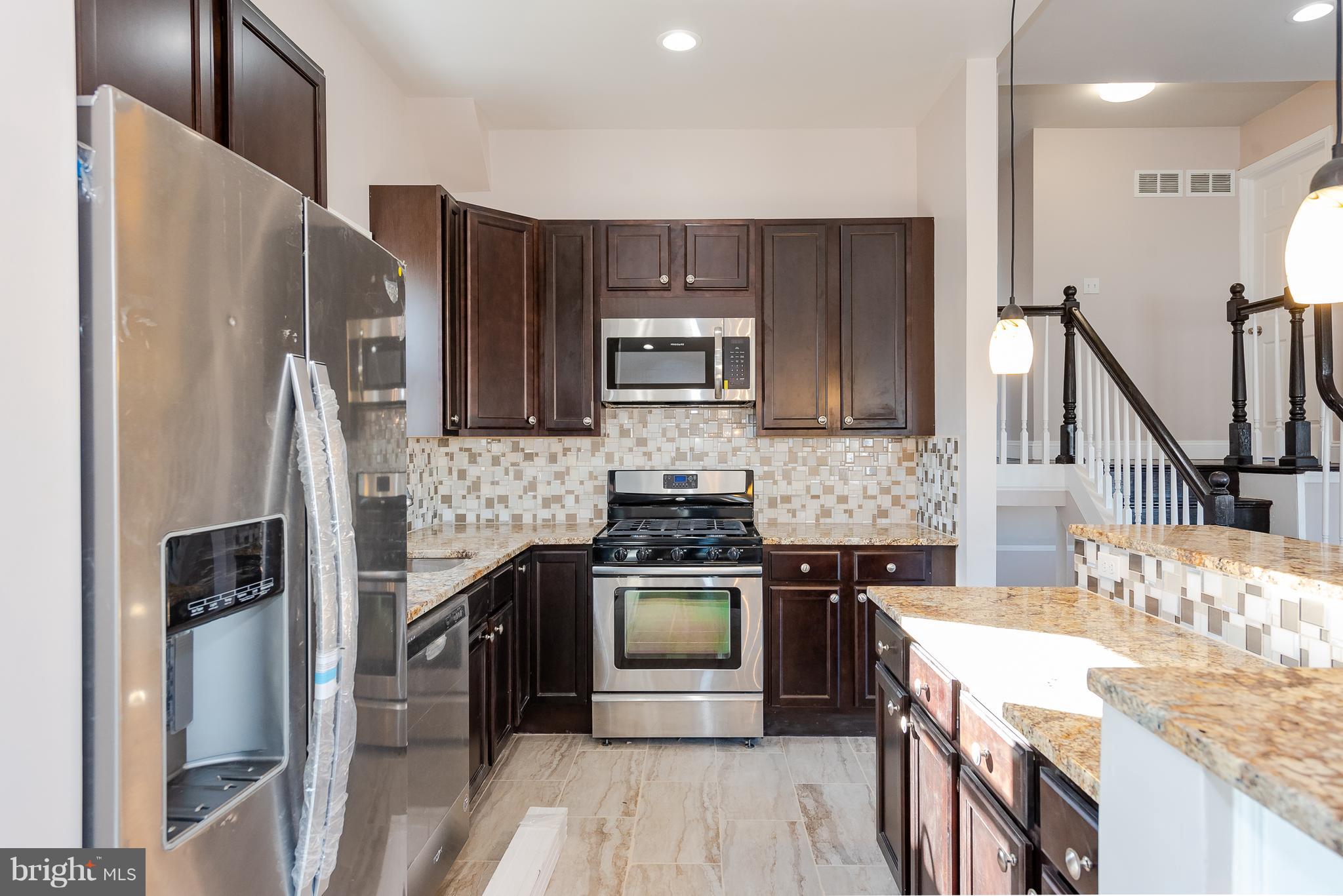3327 Essex Road Baltimore, MD 21207 - Photo 7 of 35 a kitchen with a refrigerator sink and wooden cabinets