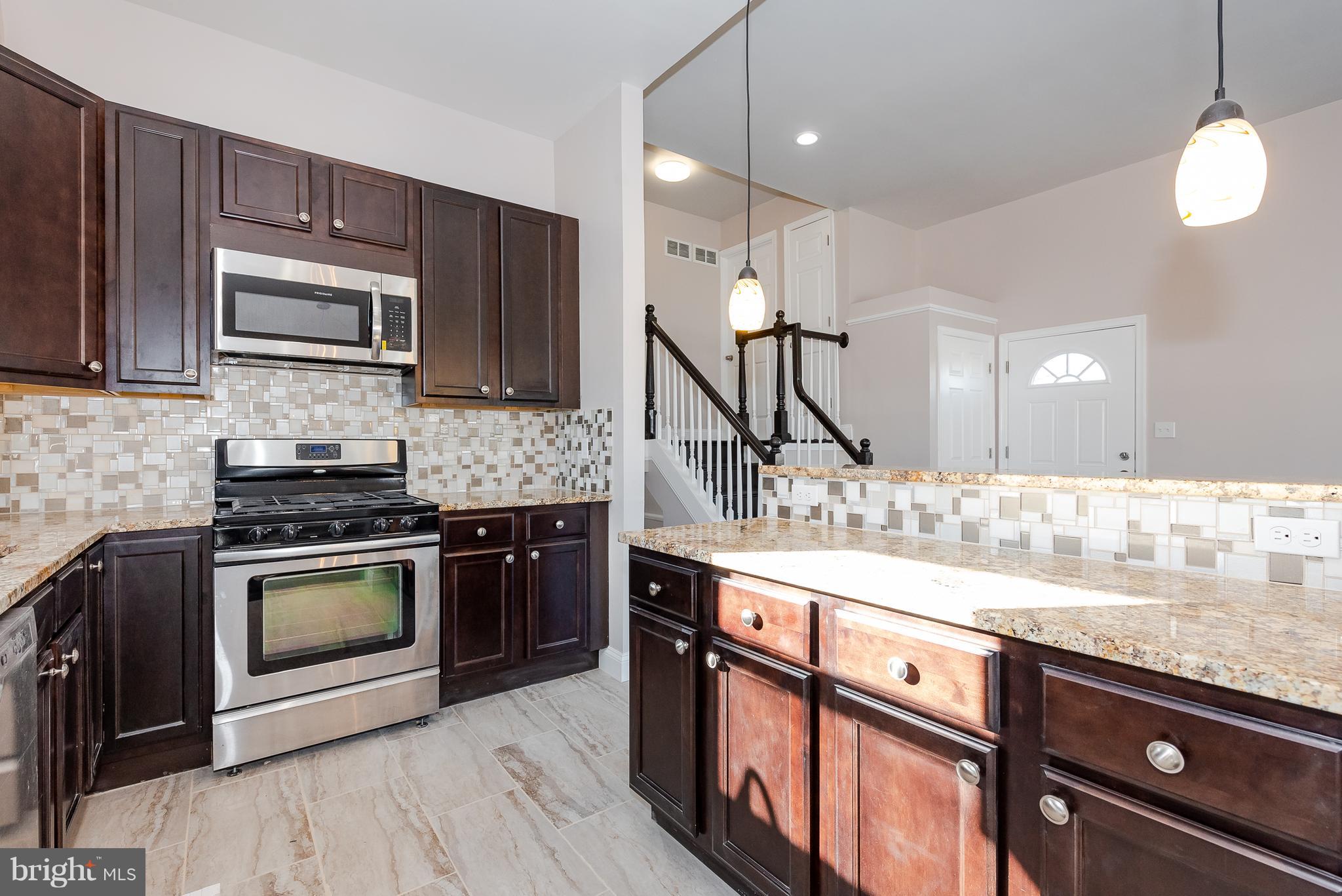 3327 Essex Road Baltimore, MD 21207 - Photo 10 of 35 a kitchen with stainless steel appliances granite countertop a stove a sink and a microwave