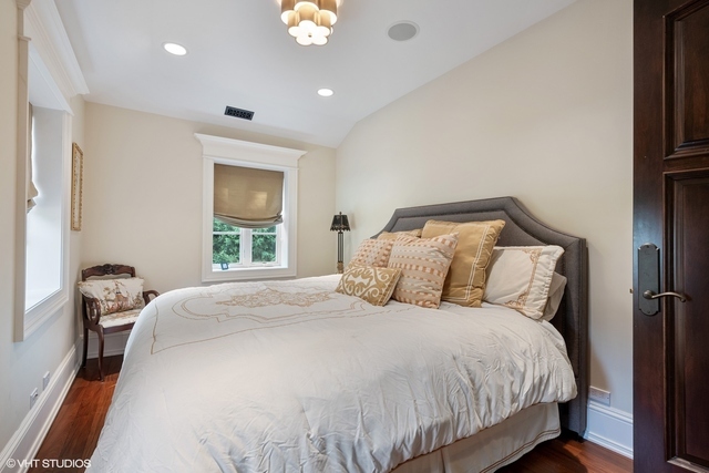 145 Oxford Road Kenilworth, IL 60043 - Photo 48 of 66 a large bed sitting in a bedroom next to a window and a chandelier