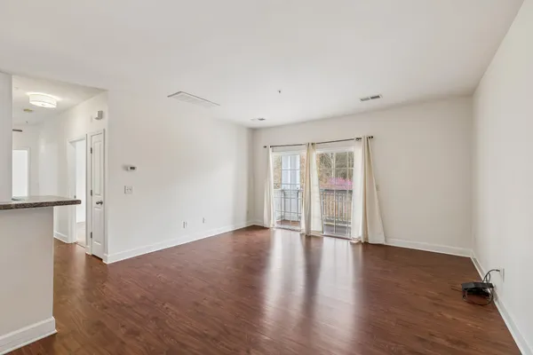a view of an empty room with wooden floor and a window