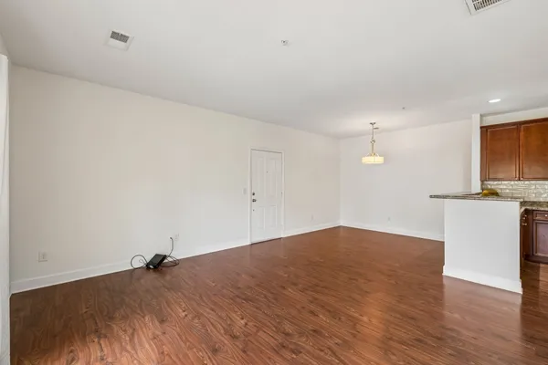 a view of kitchen and empty room with wooden floor