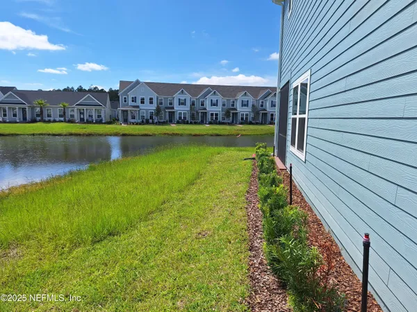 a view of a large pool with lawn chairs and large trees