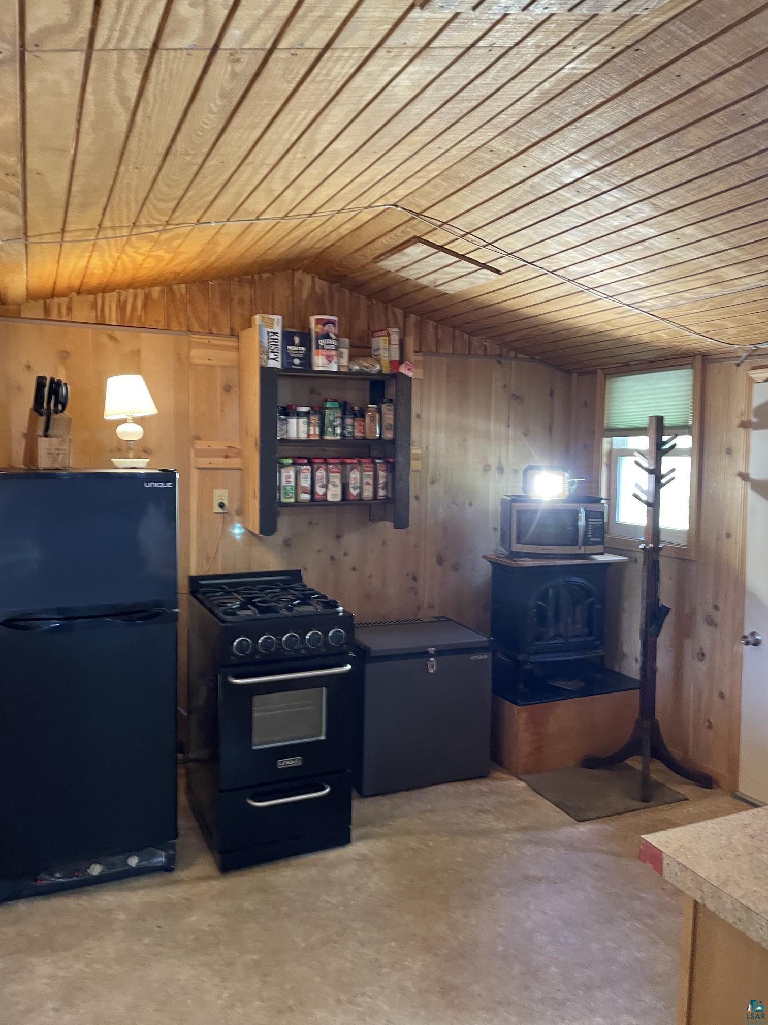 1152 Fernberg Road Ely, MN 55731 - Photo 6 of 24 Kitchenette featuring a black gas range with oven, a black compact refrigerator, and a dark chest freezer