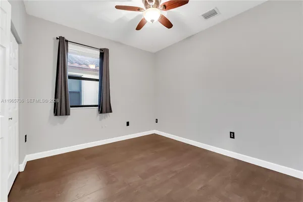 an empty room with a window and a ceiling fan