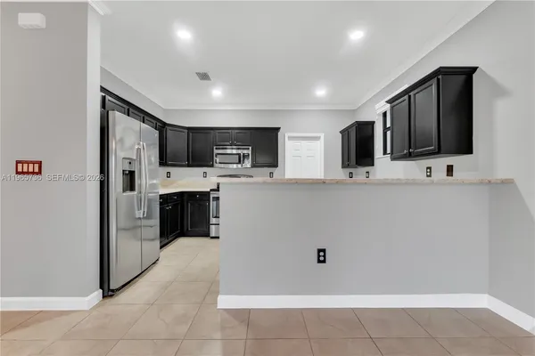 a large kitchen with stainless steel appliances kitchen island granite countertop a refrigerator and a stove top oven