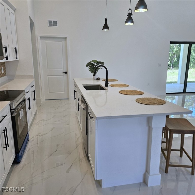 113 Monroe Avenue Lehigh Acres, FL 33936 - Photo 4 of 24 a kitchen with a sink a stove and chairs
