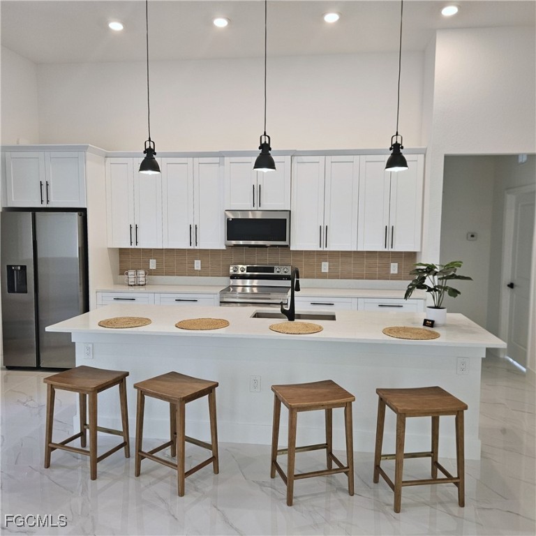113 Monroe Avenue Lehigh Acres, FL 33936 - Photo 5 of 24 a kitchen with stainless steel appliances granite countertop a sink a stove a refrigerator cabinets and chairs