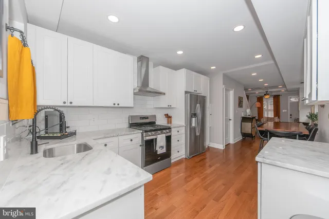 a kitchen with stainless steel appliances kitchen island granite countertop a sink refrigerator and cabinets