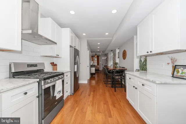 a kitchen with stainless steel appliances granite countertop a stove top oven a sink dishwasher and a refrigerator with wooden floor