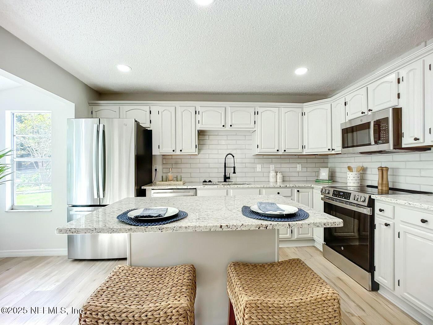 8735 Moss Haven Road Jacksonville, FL 32221 - Photo 8 of 29 a kitchen with stainless steel appliances granite countertop a sink dishwasher a stove a microwave oven and white cabinets with wooden floor