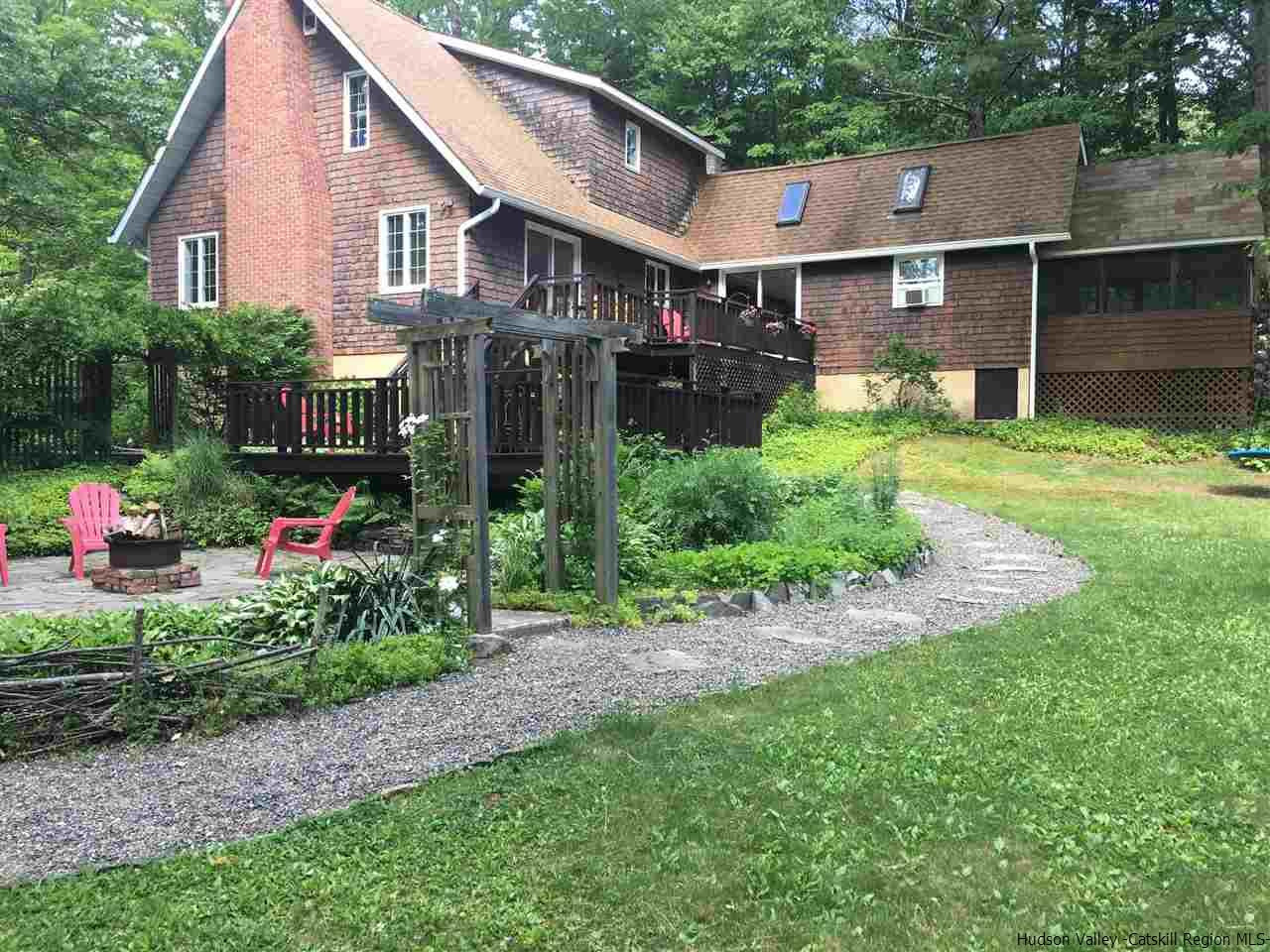 a view of a house that has a bunch of plants and trees in the background