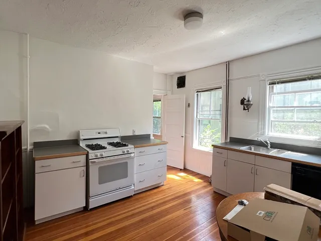 a kitchen with a stove a sink and wooden floor