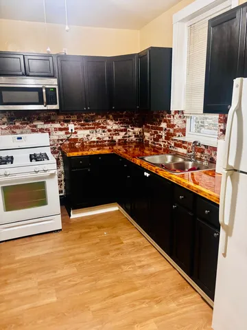 a kitchen with stainless steel appliances kitchen island granite countertop a stove refrigerator and cabinets