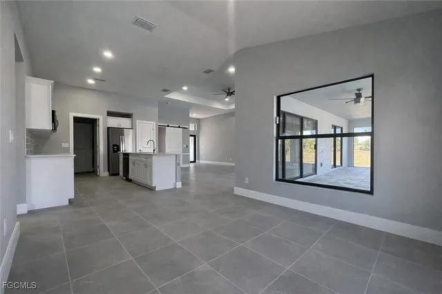 a view of an empty room with a window and kitchen view