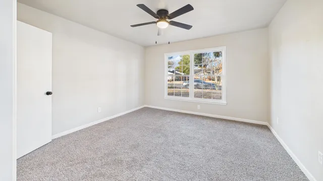 an empty room with windows and ceiling fan