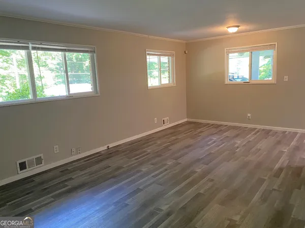 a view of an empty room with window and wooden floor