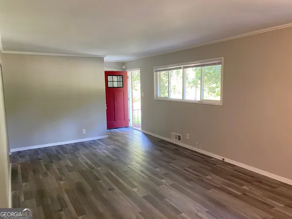 a view of an empty room with wooden floor and a window
