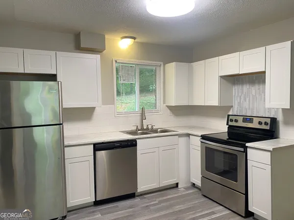 a kitchen with granite countertop a sink stove and cabinets