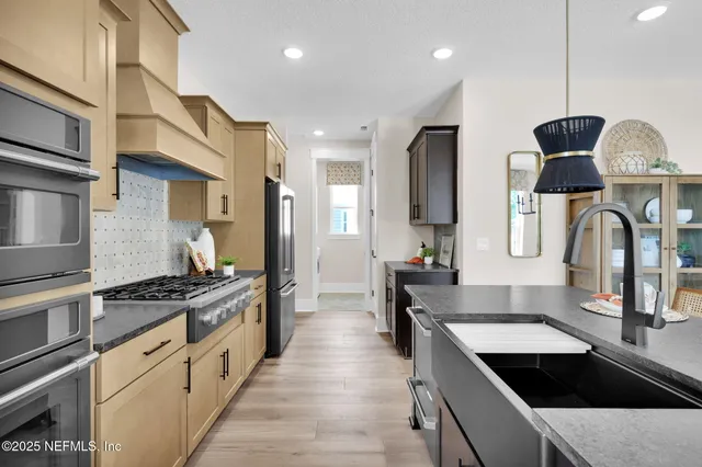 a view of a dining room and livingroom with furniture wooden floor a rug a flat screen tv a painting and a chandelier