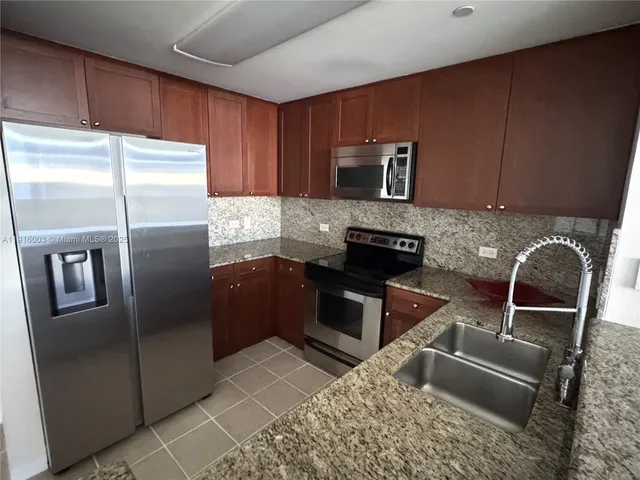 a kitchen with stainless steel appliances granite countertop a refrigerator and a stove top oven