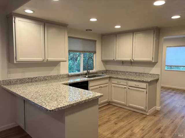 a kitchen with granite countertop cabinets sink and window