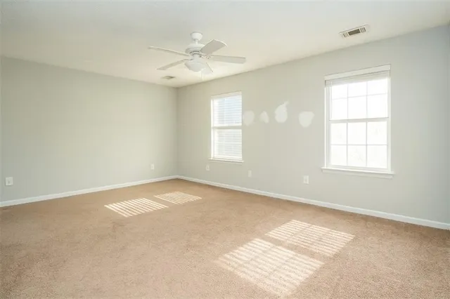 an empty room with windows and fan