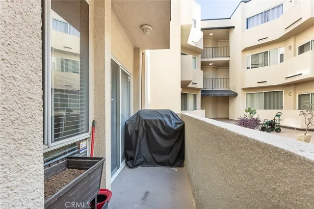a view of a patio that has couple of cars parked in front of a house