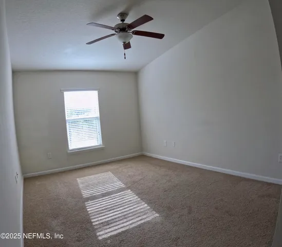 an empty room with a window and a fan