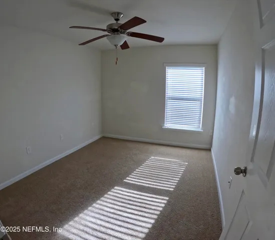 a view of a bedroom with a ceiling fan and a window