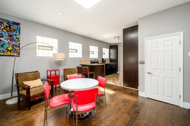 a kitchen with stainless steel appliances kitchen island granite countertop a dining table chairs and a refrigerator