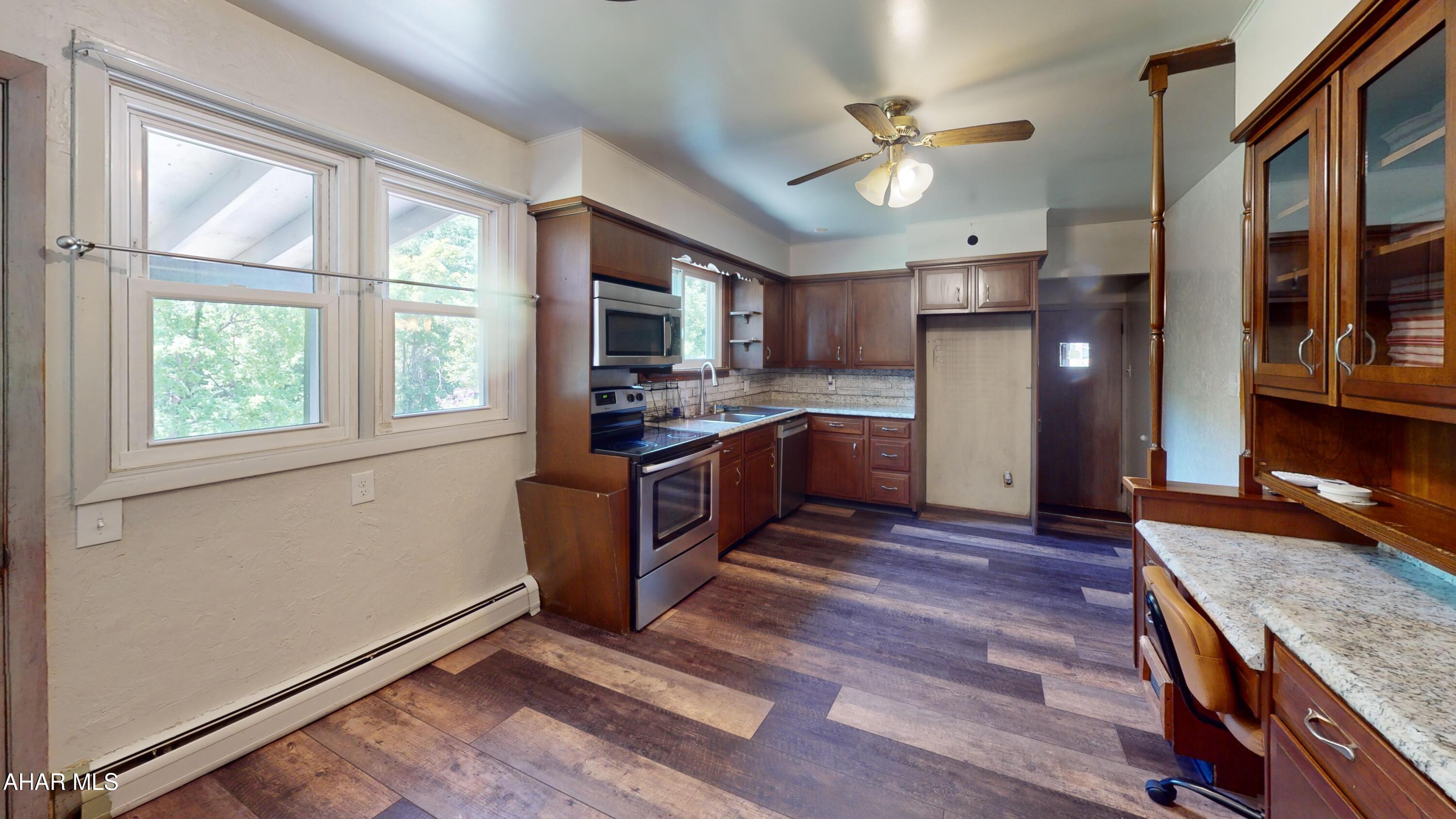871 Decker Hollow Road Tyrone, PA 16686 - Photo 31 of 35 a kitchen with stainless steel appliances granite countertop a refrigerator a sink dishwasher a stove and a dining table with wooden floor