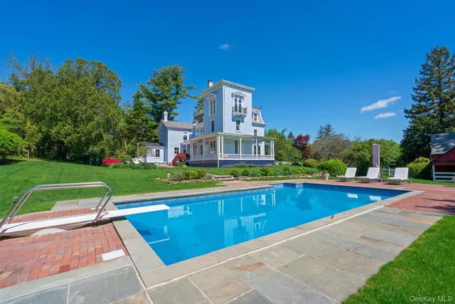 a view of swimming pool that has lawn chairs with plants and trees