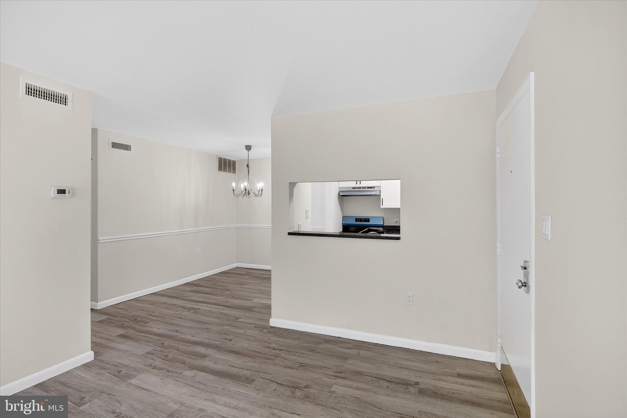 10340 Luria Commons Court, Unit 3H Burke, VA 22015 - Photo 5 of 21 a view of a refrigerator in kitchen and an empty room with wooden floor