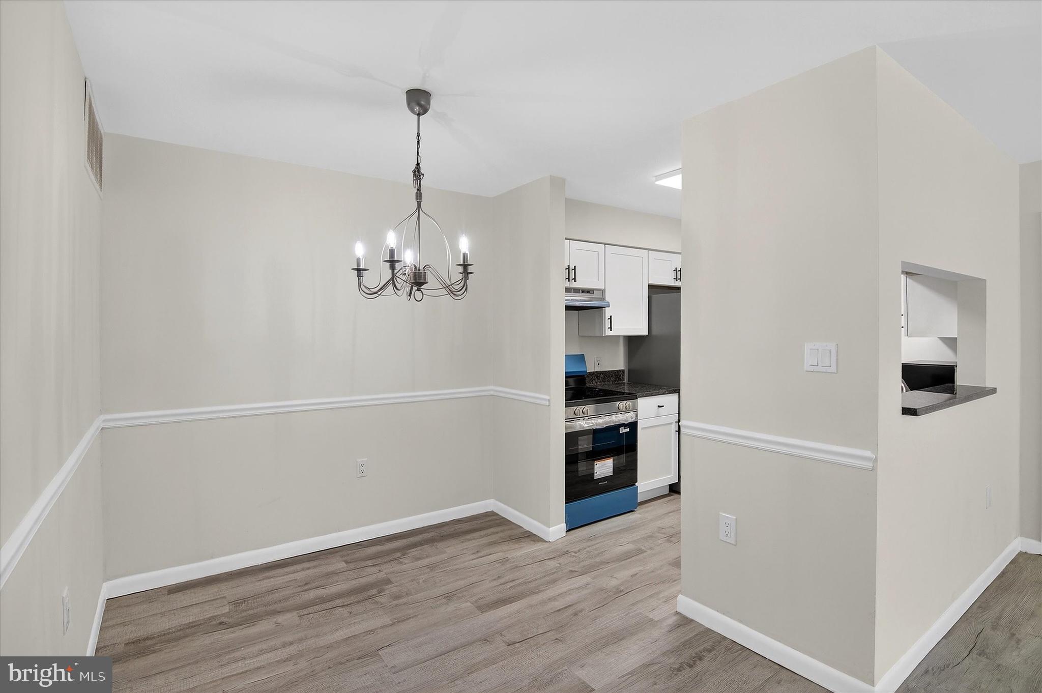 10340 Luria Commons Court, Unit 3H Burke, VA 22015 - Photo 7 of 21 a view of a kitchen with a refrigerator a stove top oven and wooden floor