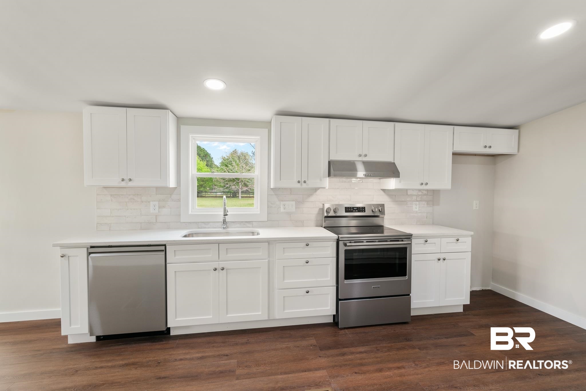 12645 Breman Road Elberta, AL 36530 - Photo 14 of 44 Kitchen featuring a sink, stainless steel appliances, baseboards, and under cabinet range hood