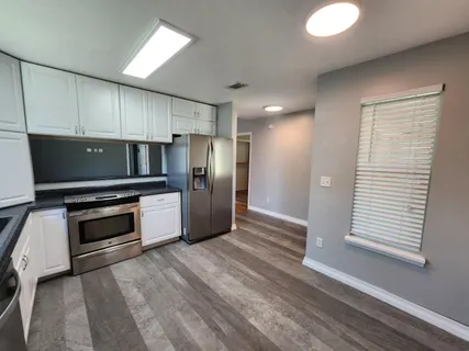 a kitchen with granite countertop a refrigerator and a stove top oven