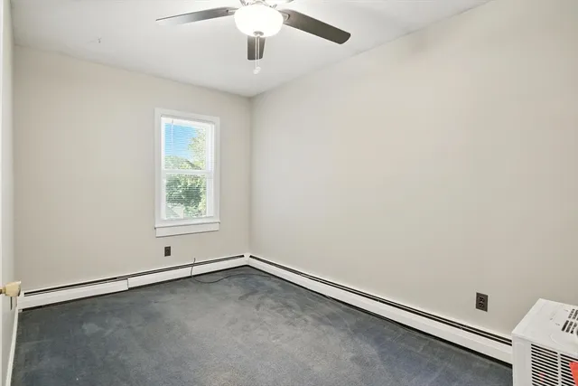 an empty room with a window and ceiling fan