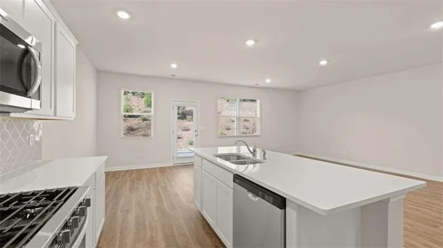 a kitchen with stainless steel appliances a white stove top oven cabinets and a wooden floor