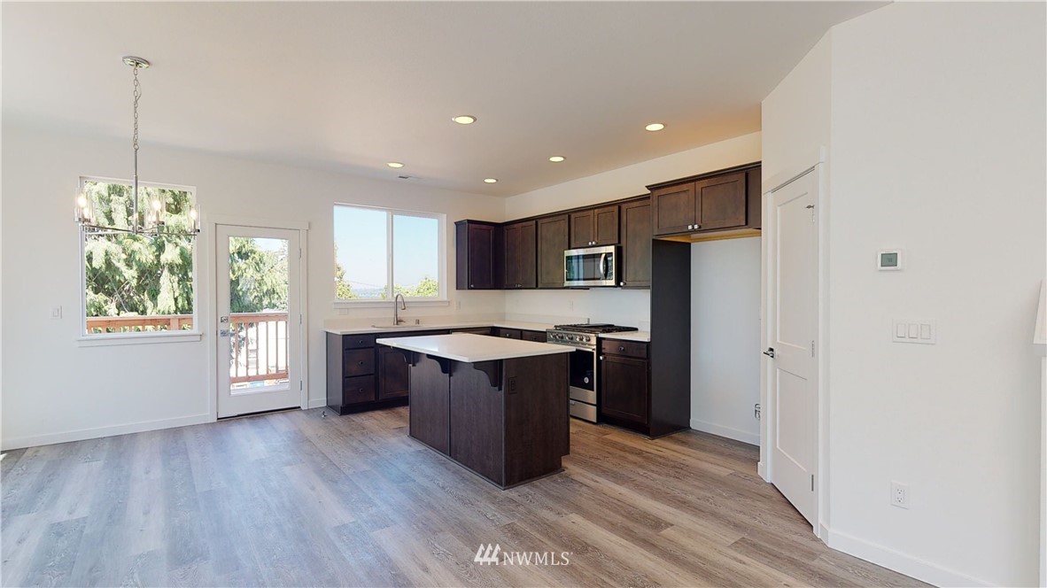 320 South 48th Street, Unit H19 Renton, WA 98055 - Photo 3 of 29 a large kitchen with stainless steel appliances granite countertop a refrigerator a sink dishwasher a stove and a wooden floor