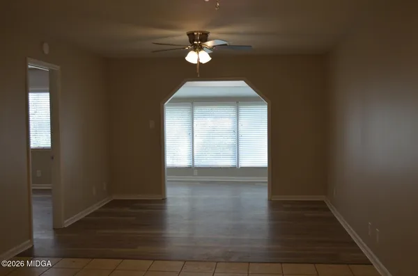 a view of an empty room with chandelier fan and windows