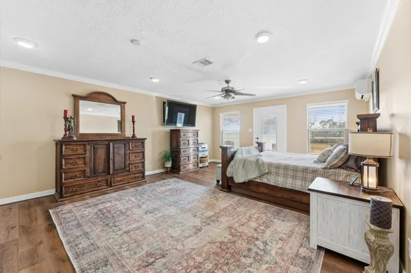 a spacious bedroom with a bed a dresser and large windows