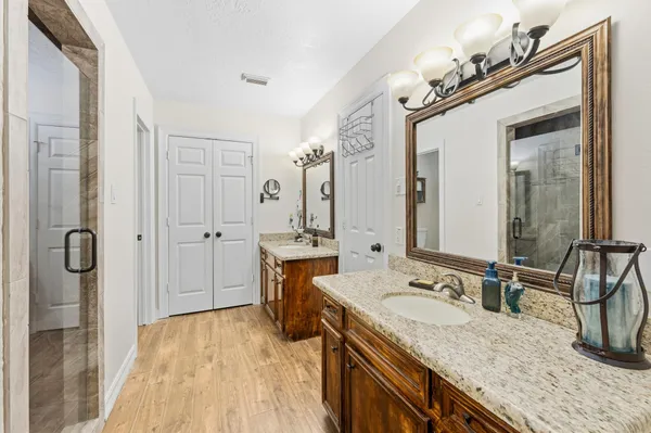 a bathroom with a granite countertop sink a mirror a vanity and shower